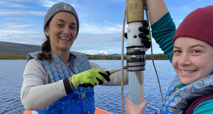 Sediment core tube held in a small boat on a lake.